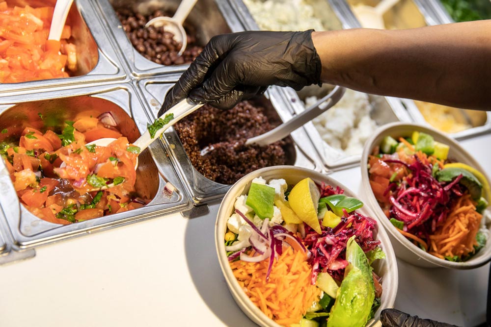 Närbild på medarbetare som lägger ihop en fräsch och nyttig bowl